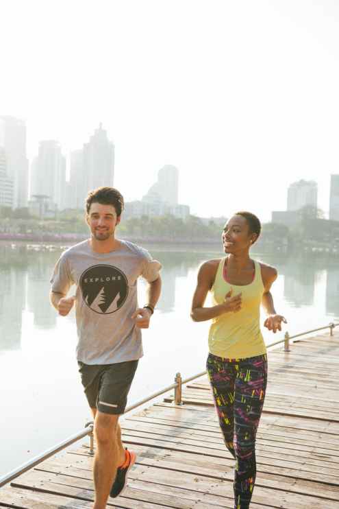 man and woman jogging near body of water